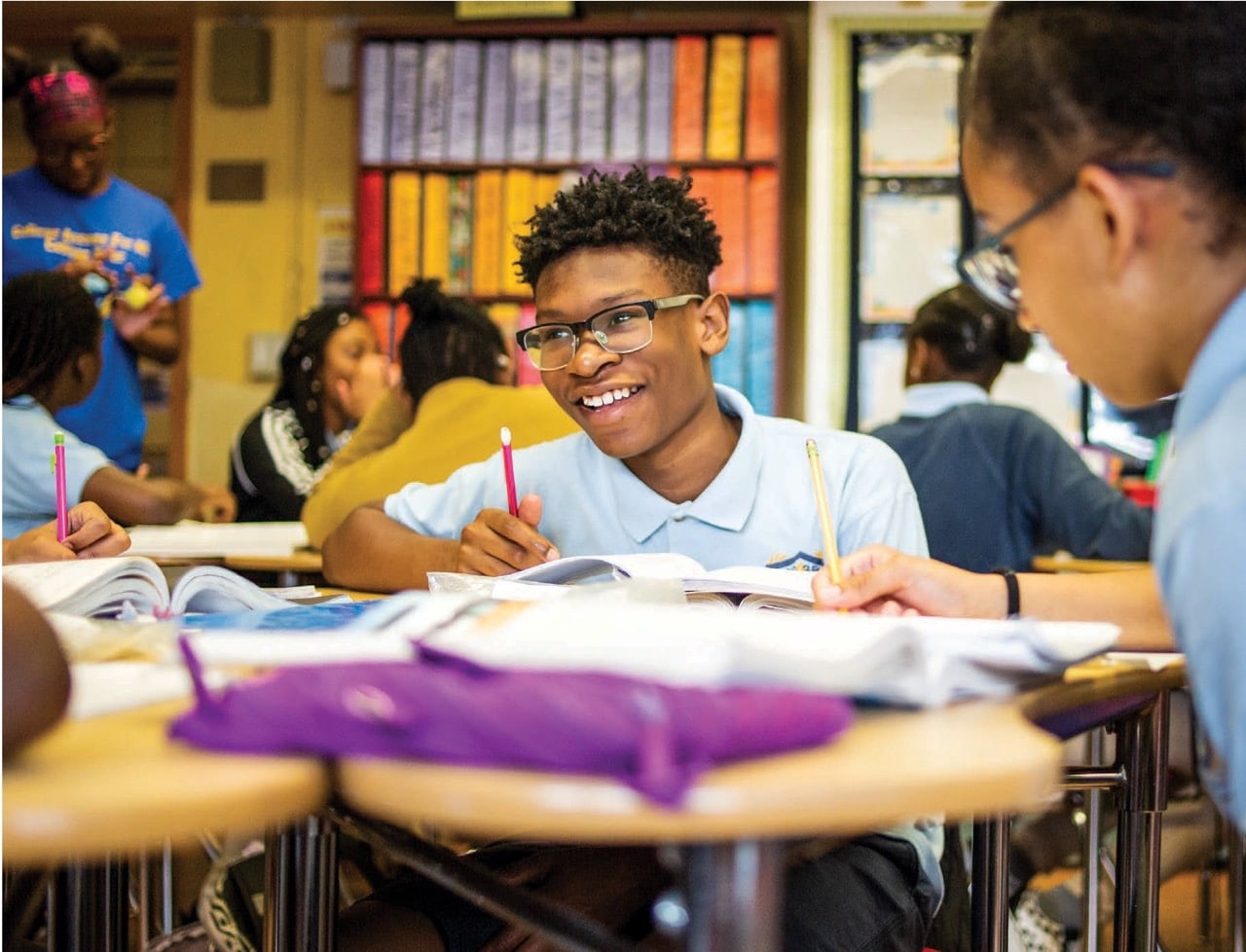 Counseling In Schools comparte El impacto de la Iniciativa de Escuelas Comunitarias de NYC. Alumno seguro de sí mismo sonriendo en su pupitre