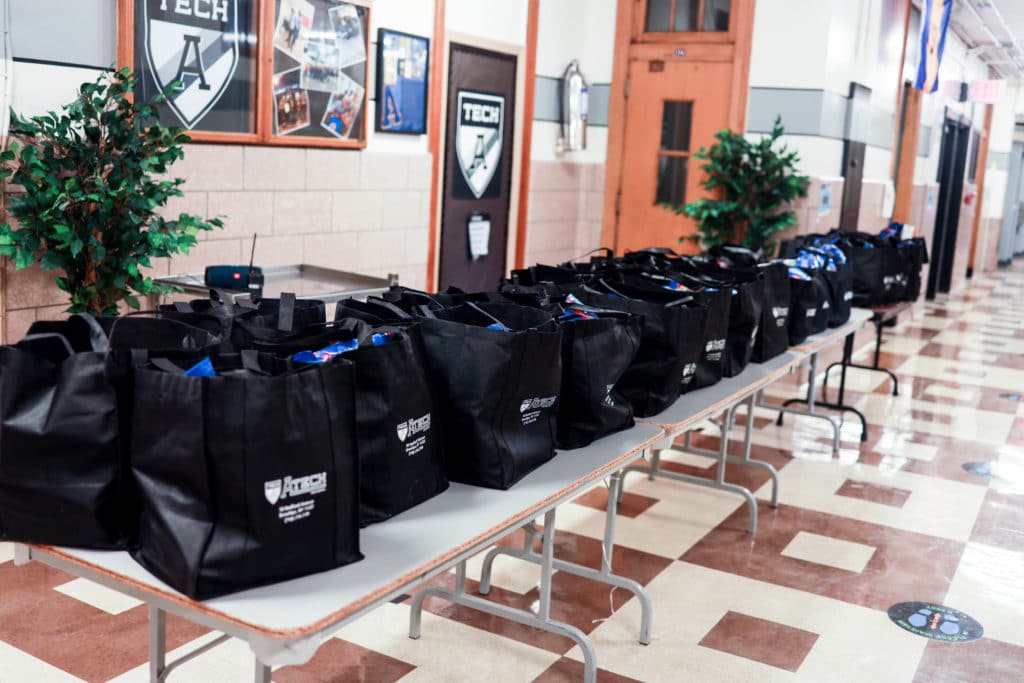 Counseling In Schools shares: Holiday "gift bags" filled with food and paper goods sit lined up on a table before families and students arrive to collect them.